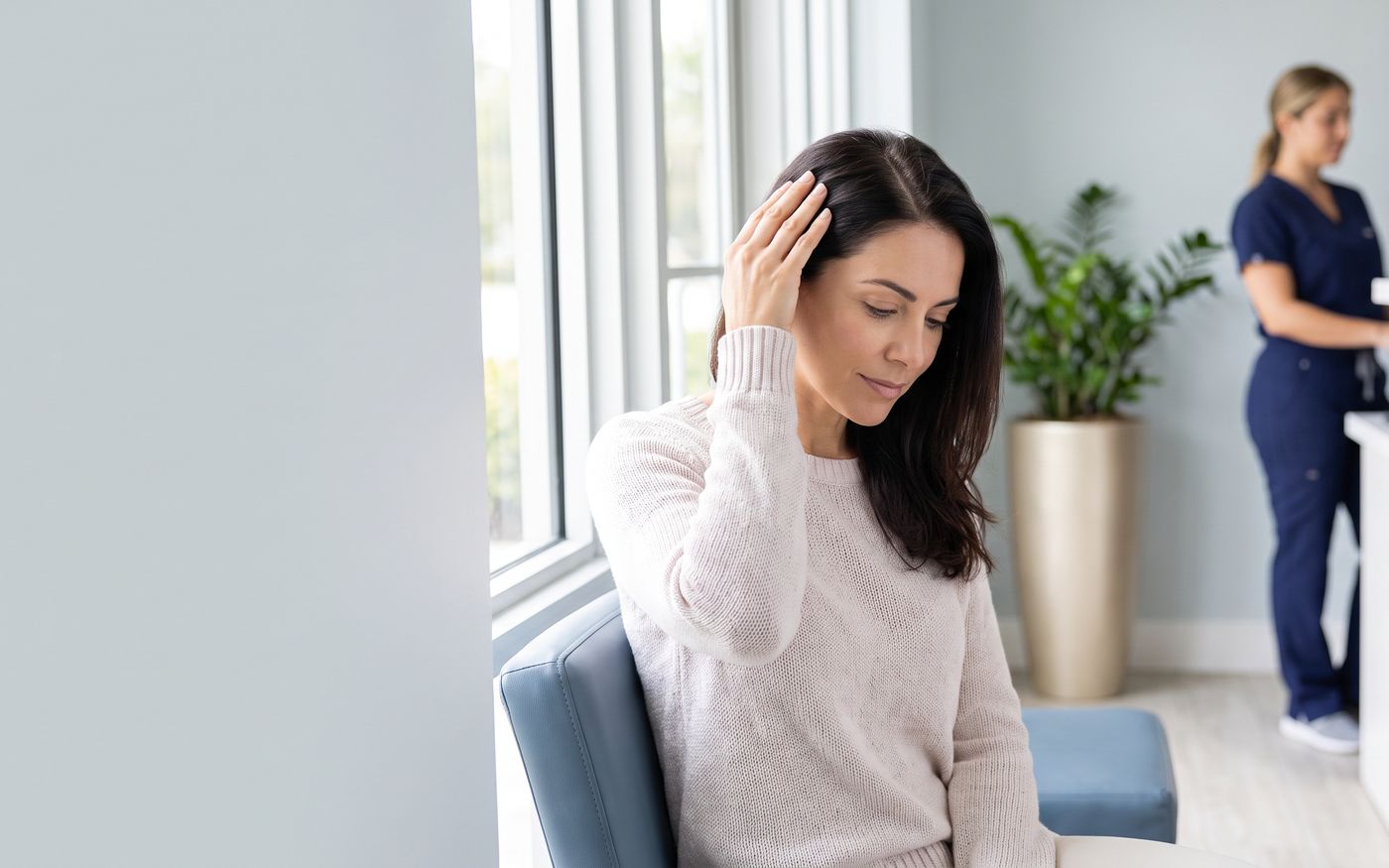 Donna che separa i capelli vicino alla finestra durante la consulenza per il trapianto femminile